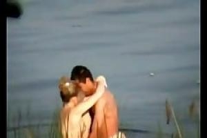 Amateur couple is making love on the beach  while a bad voyeur is recording a video