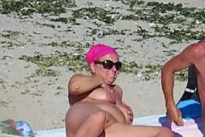 Naked woman are enjoying on the beach  although some guys are around and having fun